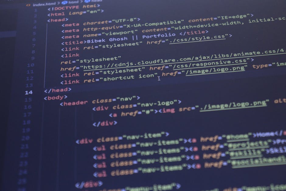 A close-up view of a modern desktop computer monitor placed on a desk in an office setting, displaying multiple lines of colorful HTML and JavaScript code. The screen shows syntax highlighting with re